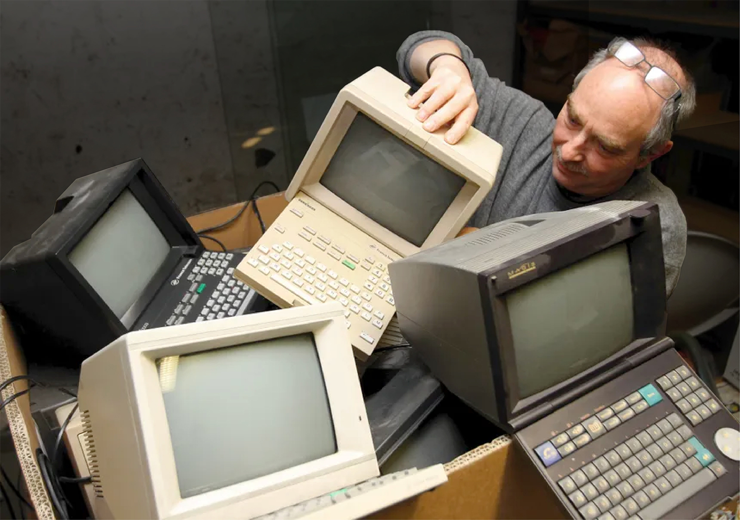 Man going through a box filled with old minitel terminals
